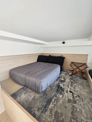 A bedroom with a bed, a headboard, a small wooden side table, and a patterned rug. - Torre Nous | A Pasos de Chapultepec+Seguridad 24/7 (Guadalajara)