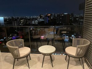 A balcony with wicker chairs and a small round table, overlooking a cityscape at night. - Torre Nous | A Pasos de Chapultepec+Seguridad 24/7 (Guadalajara)