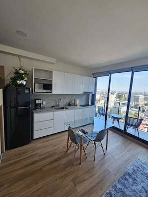 A modern kitchen with a dining area and large windows. - Torre Nous | A Pasos de Chapultepec+Seguridad 24/7 (Guadalajara)