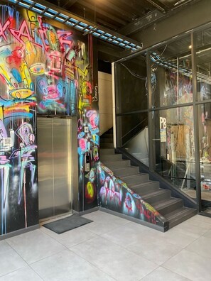 Una escala amb art de grafiti a les parets i una porta de vidre amb un cartell.