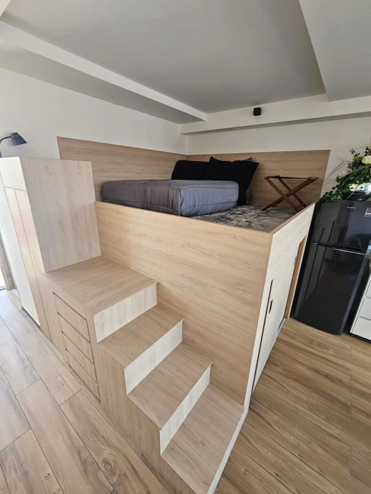 Ein modernes Schlafzimmer im Loft-Stil mit einer eingebauten Bettenzeile, einer kleinen Küchenzeile und einer Treppe.