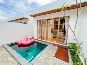 Uma casa moderna com piscina, um flamingue rosa inflável e uma janela grande.