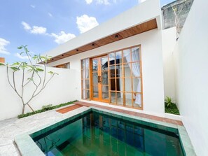 Een modern huis met een zwembad, grote ramen en een houten terras.