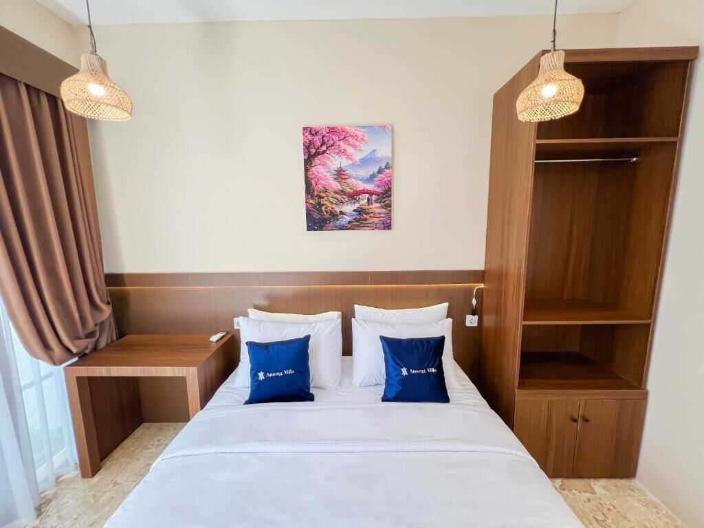 Habitación de hotel con cama, mesitas de noche, un armario de madera y un cuadro en la pared.