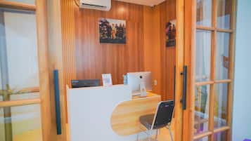 Mostrador de recepción con computadora, silla y paneles de madera.