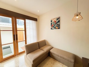 Una habitación con un sofá color beige, una puerta corredera de vidrio y una lámpara colgante.