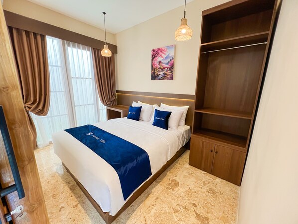 A hotel room with a large bed, a wooden wardrobe, a nightstand, and a painting on the wall.