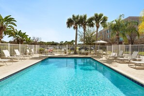 A rectangular swimming pool with clear blue water, surrounded by white lounge chairs and palm trees. - 1 Qn Studio w/ Kitchen | Free Breakfast & Pool (Tampa)