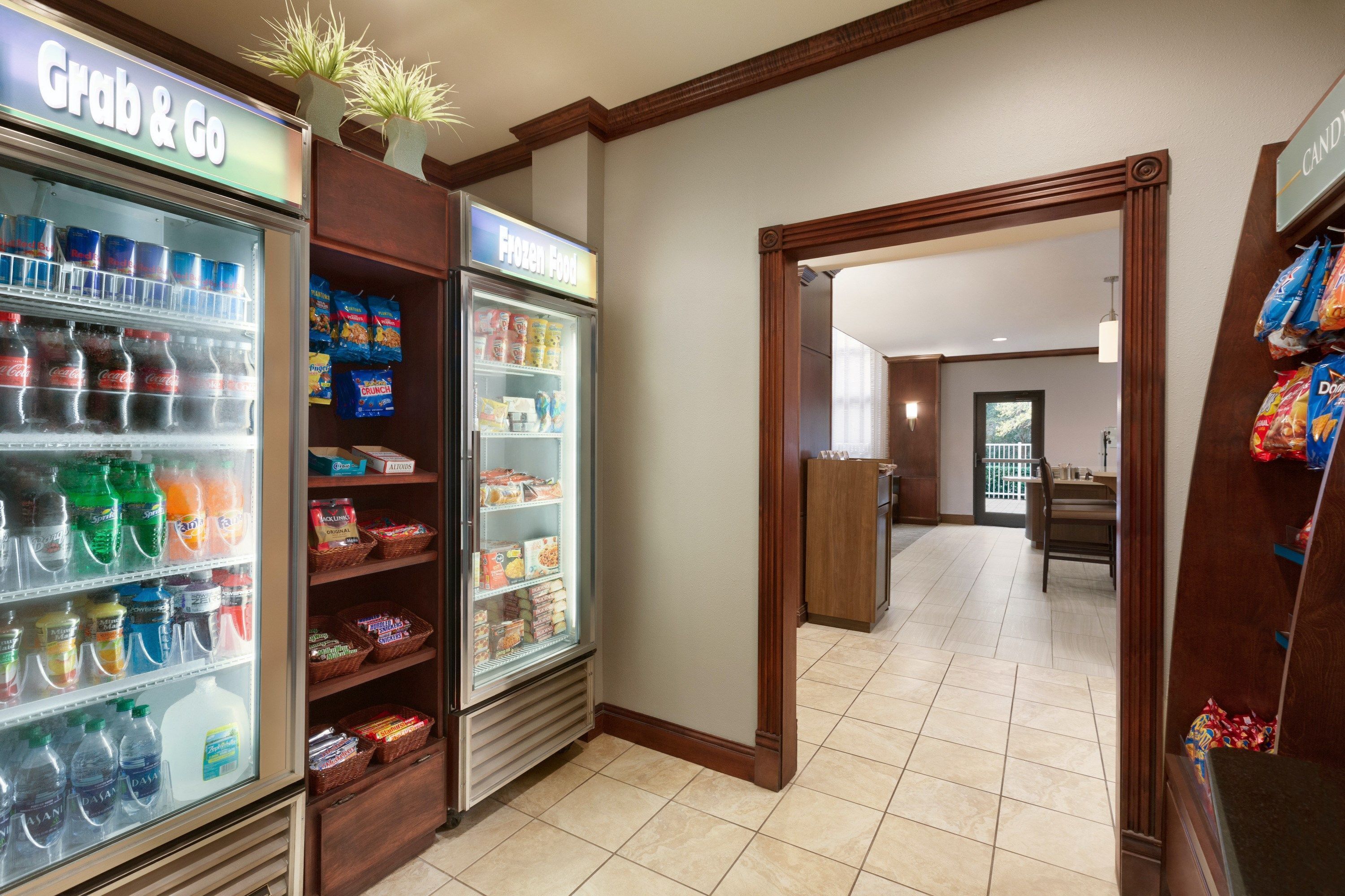Un vestíbulo de hotel con un expositor refrigerado tipo 'Grab & Go' y una sección de alimentos congelados.