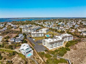 A coastal residential area with multiple apartment buildings, a parking lot, and a swimming pool. - 3BR Direct Ocean Front Condo @ The Point! Point Emerald Villas A209 (Emerald Isle)