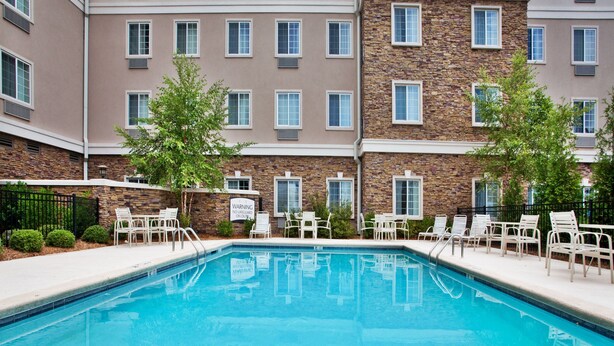A swimming pool with lounge chairs and a warning sign.