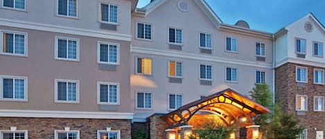 A multi-story hotel with a central entrance featuring a stone facade and a covered walkway.