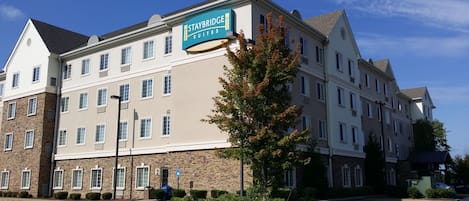 Un hotel Staybridge Suites con fachada de piedra, varias ventanas y un cartel que indica que es un hotel.
