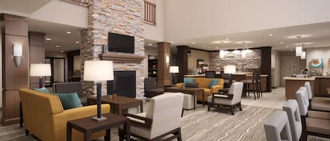 A hotel lobby with a stone fireplace, seating area, and a bar.