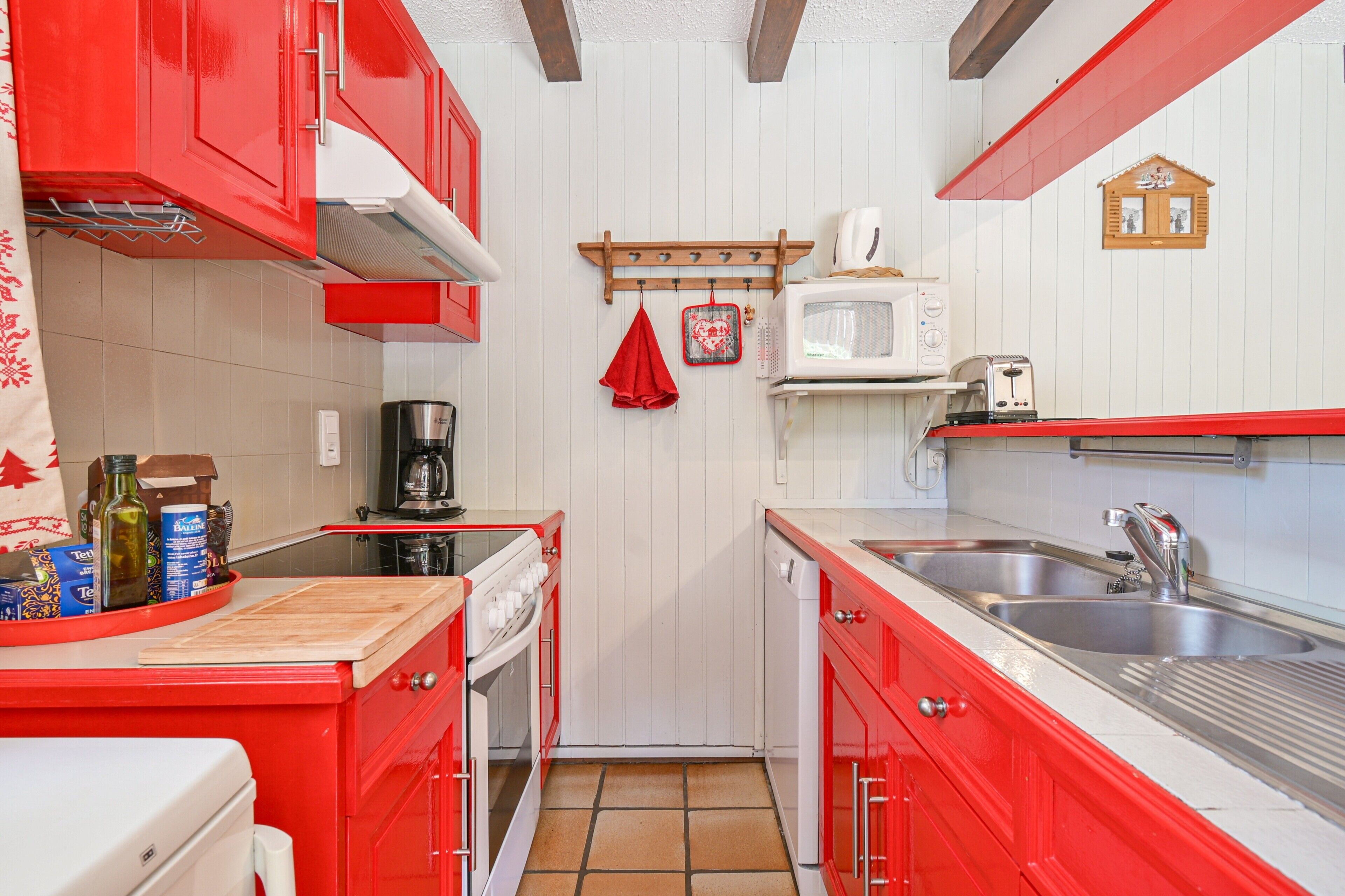 Cocina compacta con armarios rojos, un microondas, un tostador y una cafetera.