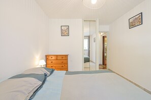 Ein Schlafzimmer mit einem Bett, einer Holzkommode und einer Tür zu einem anderen Raum.