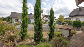 A residential area with multiple houses, a wooden fence, and a variety of trees.