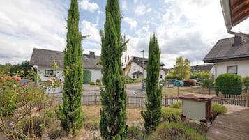 A residential area with multiple houses, a wooden fence, and a variety of trees.