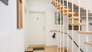 A staircase with wooden steps and white railings, leading to a door with a small decorative item on the wall.