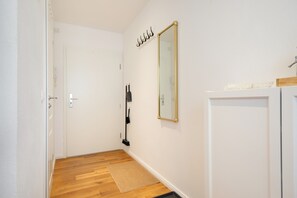 A hallway with a white door, a mirror with a gold frame, and a broom leaning against the wall.