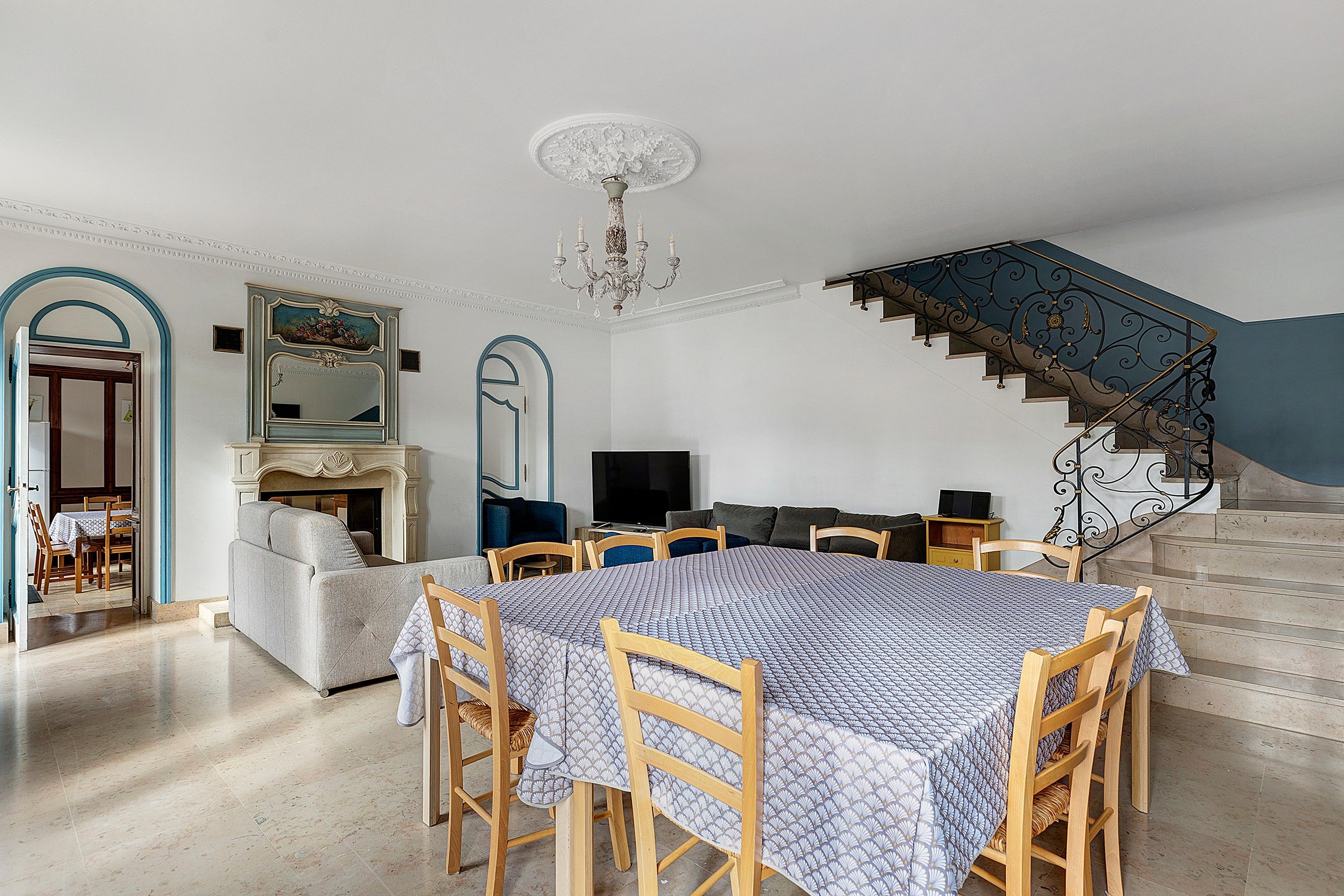 A spacious living area with a dining table, sofas, and a staircase.