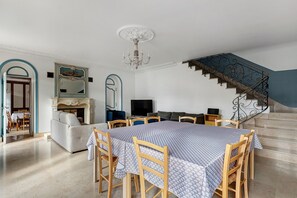 Ein geräumiger Wohnbereich mit Esstisch, Sofas und einer Treppe.