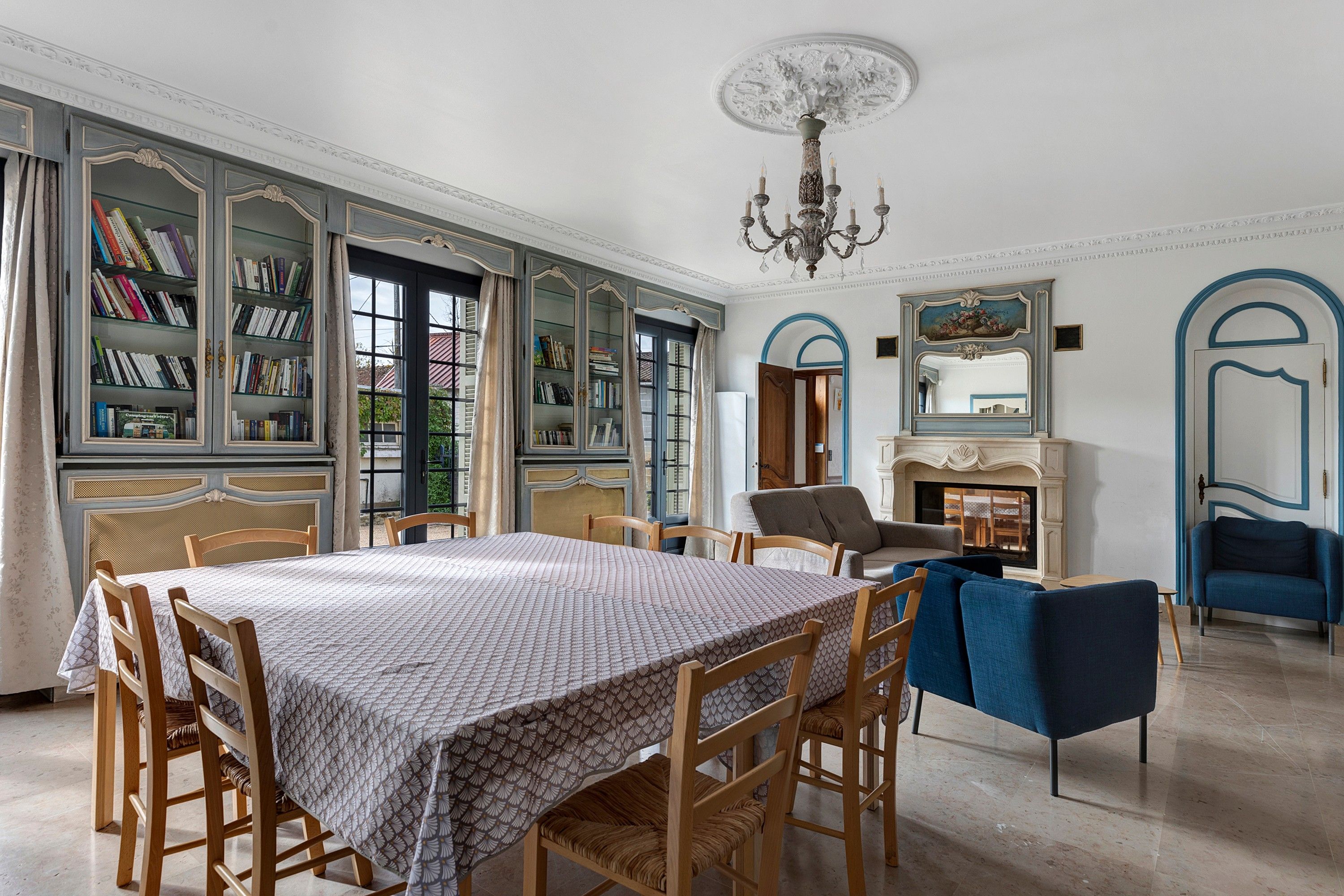 A spacious room with a large dining table, bookshelves, a sofa, and a fireplace.