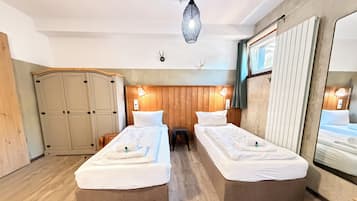 Ein Hotelzimmer mit zwei Betten, einem Holz-Kopfteil, einem Kleiderschrank und einem Spiegel.