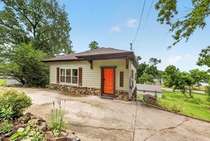 A small single-story house with a stone foundation, a red door, and a mailbox. - Monte Ne Lakehouse - Lake View (Rogers)