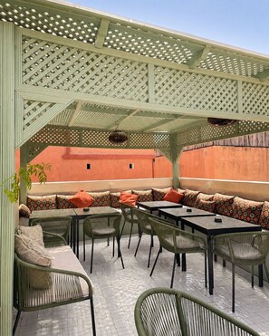 An outdoor seating area with a lattice roof, cushioned seating, and tables. - Elegant 4-Room Riad with Pool – Just Steps from the Royal Palace (Marrakech)