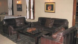 Una habitación con un sofá de cuero, una mesa de ajedrez y un cuadro en la pared.