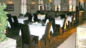 Un restaurante con varias mesas y sillas, una zona de bar y un suelo de piedra.