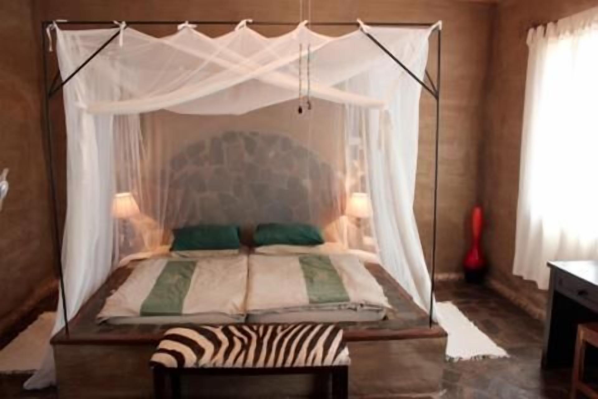 A bed with a canopy, two pillows, a bedside table, and a bench.