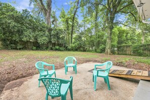 An outdoor patio area with four turquoise plastic chairs arranged around a concrete table.