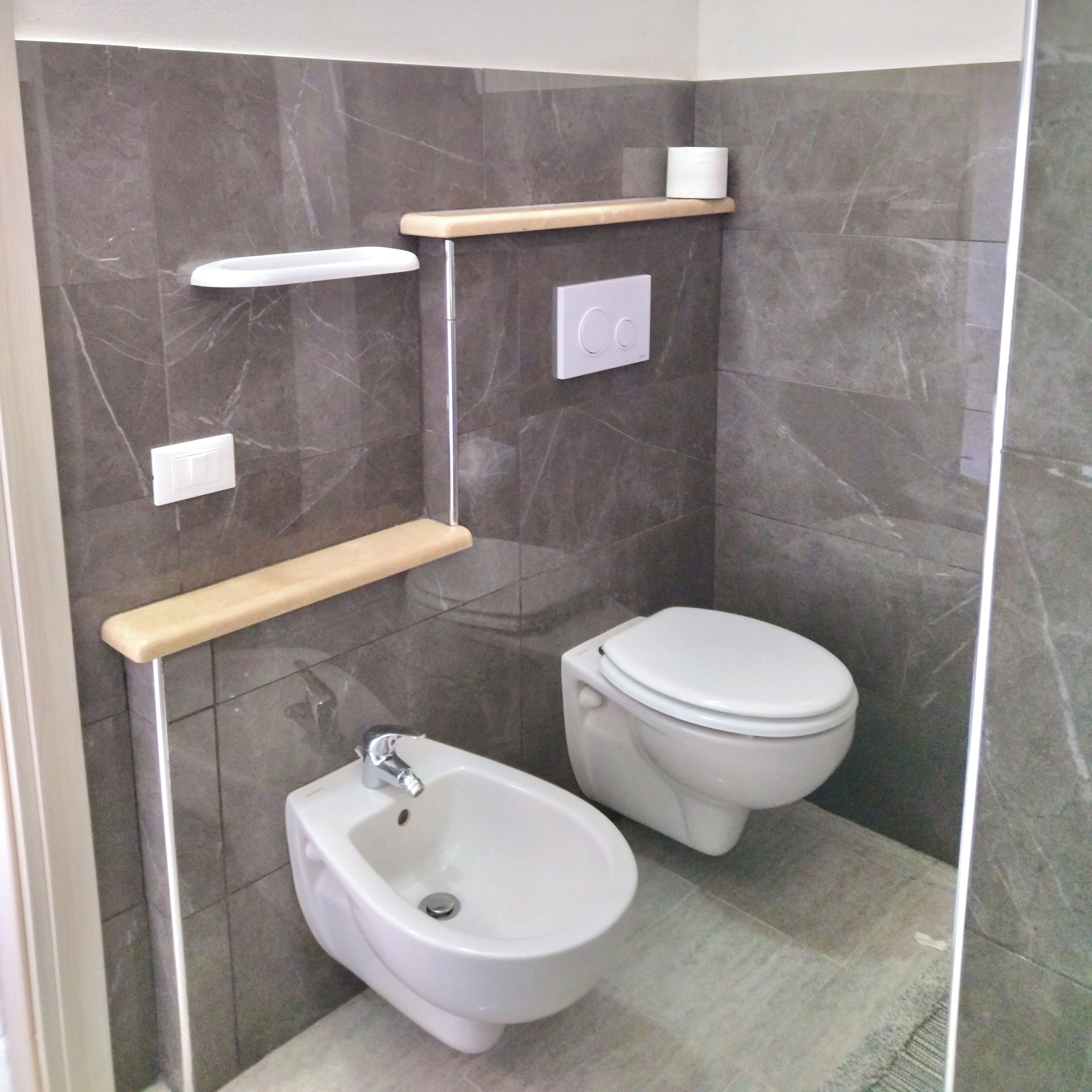 Un baño con bidé, inodoro y paredes de mármol.