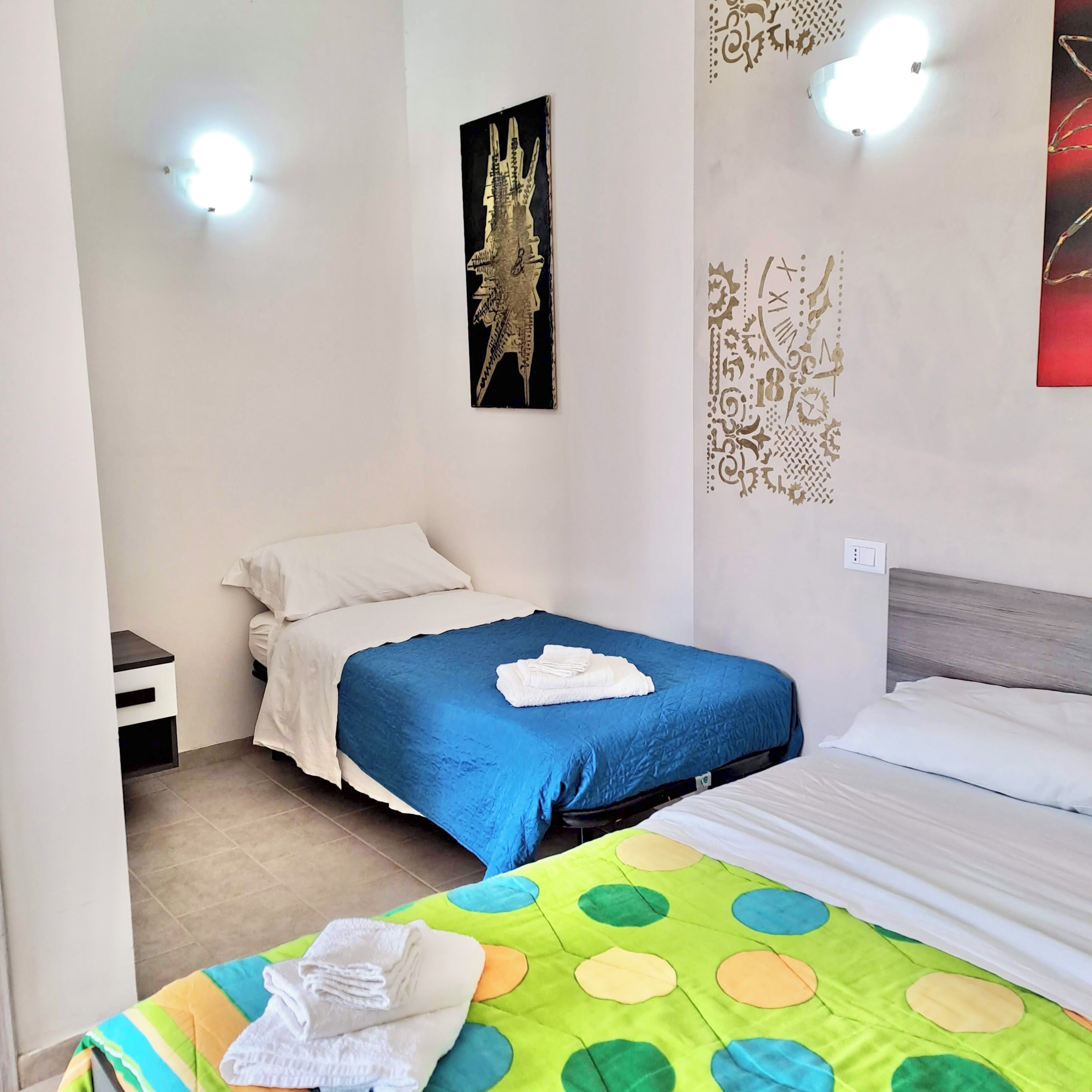 Ein Hotelzimmer mit zwei Betten, einem Nachttisch und einer Wand mit dekorativen Mustern.