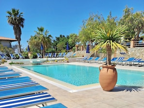 Una piscina al aire libre de temporada, sombrillas