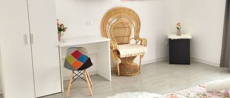 A bedroom with a bed, a desk, a chair, a TV, and a painting on the wall.