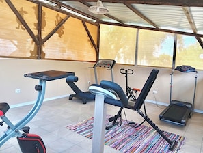 Un gimnasio con equipamiento de ejercicio, incluyendo una cinta de correr, elíptica y bicicleta estática.