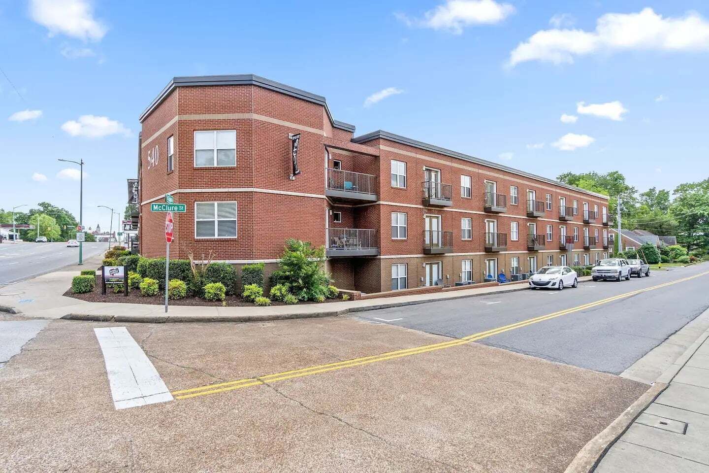 A multi-story brick building with a corner entrance, a stop sign, and a street view.