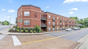 A multi-story brick building with a corner entrance, a stop sign, and a street view.