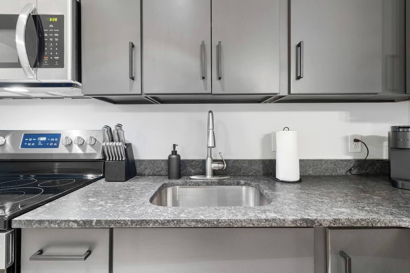 A modern kitchen with stainless steel appliances, a granite countertop, and a built-in sink.
