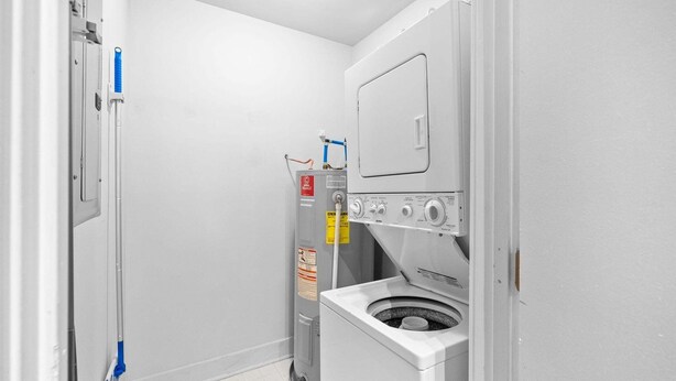 A compact laundry room with a washer and dryer, a water heater, and a mop. - The Lofts of Downtown (540 N 2nd St, #202) | Charming 2-Bedroom in the Heart of Clarksville, TN (Clarksville)