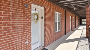 A brick building with a covered walkway, a door with a wreath, and a number '202' sign. - The Lofts of Downtown (540 N 2nd St, #202) | Charming 2-Bedroom in the Heart of Clarksville, TN (Clarksville)