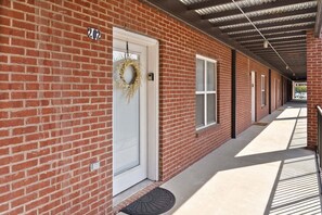 A brick building with a covered walkway, a door with a wreath, and a number '202' sign. - The Lofts of Downtown (540 N 2nd St, #202) | Charming 2-Bedroom in the Heart of Clarksville, TN (Clarksville)