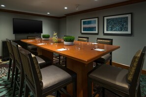 A conference room with a long wooden table, six chairs, a flat-screen TV, and framed artwork on the walls. - Chic 1BR Conference Suite | Free Breakfast + Pool (Glen Mills)