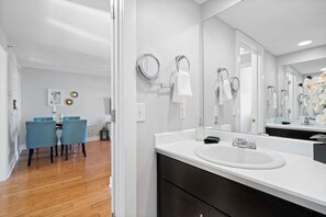 Casa de banho moderna com um espelho grande, lavatório branco e dois porta-toalhas.