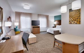 Habitació d'hotel amb un llit, una escriptori, una cadira, una televisió i un quadre a la paret.