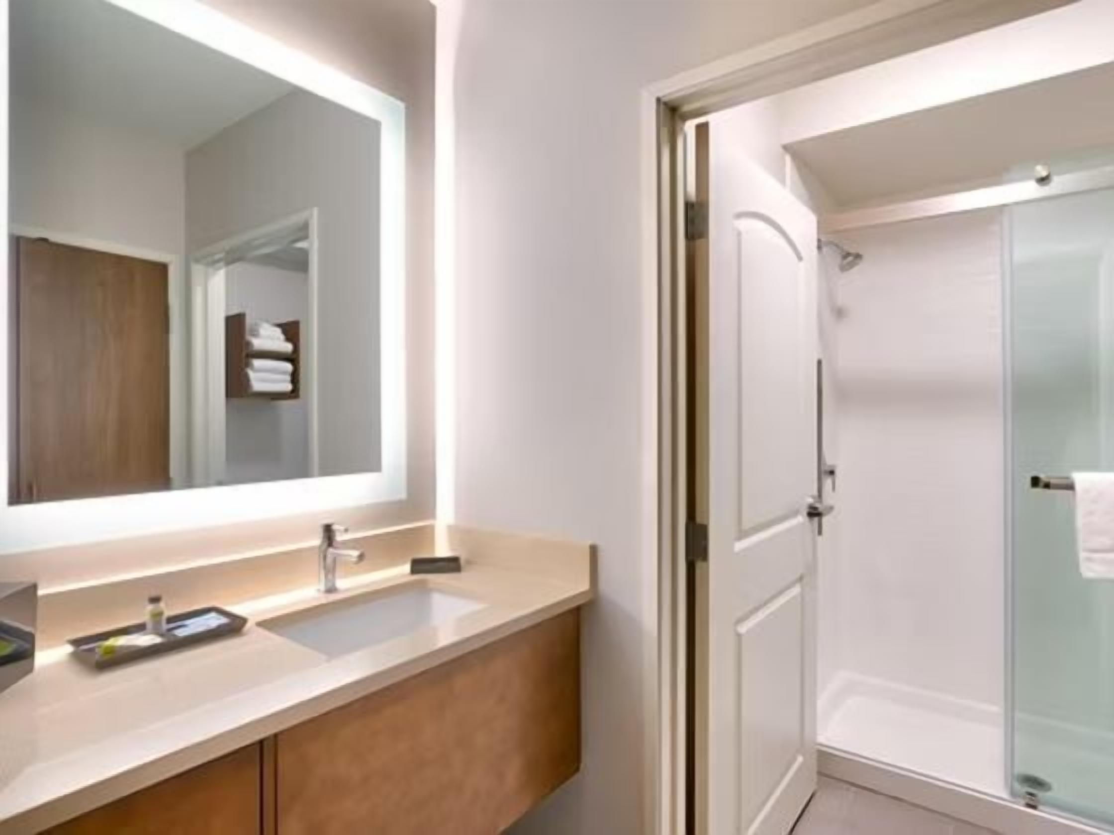 A bathroom with a double sink vanity, a large mirror, and a glass shower enclosure.