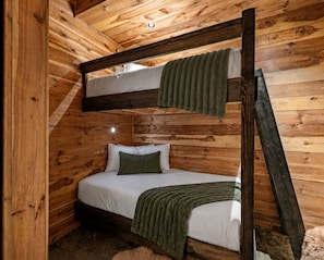 A bunk bed with a wooden ceiling and walls, a single bed below, and a ladder. - Hemlock Haven: Creekside Paradise • Pool • Sauna • HotTub • FirePit • Fun Games (Blue Ridge)